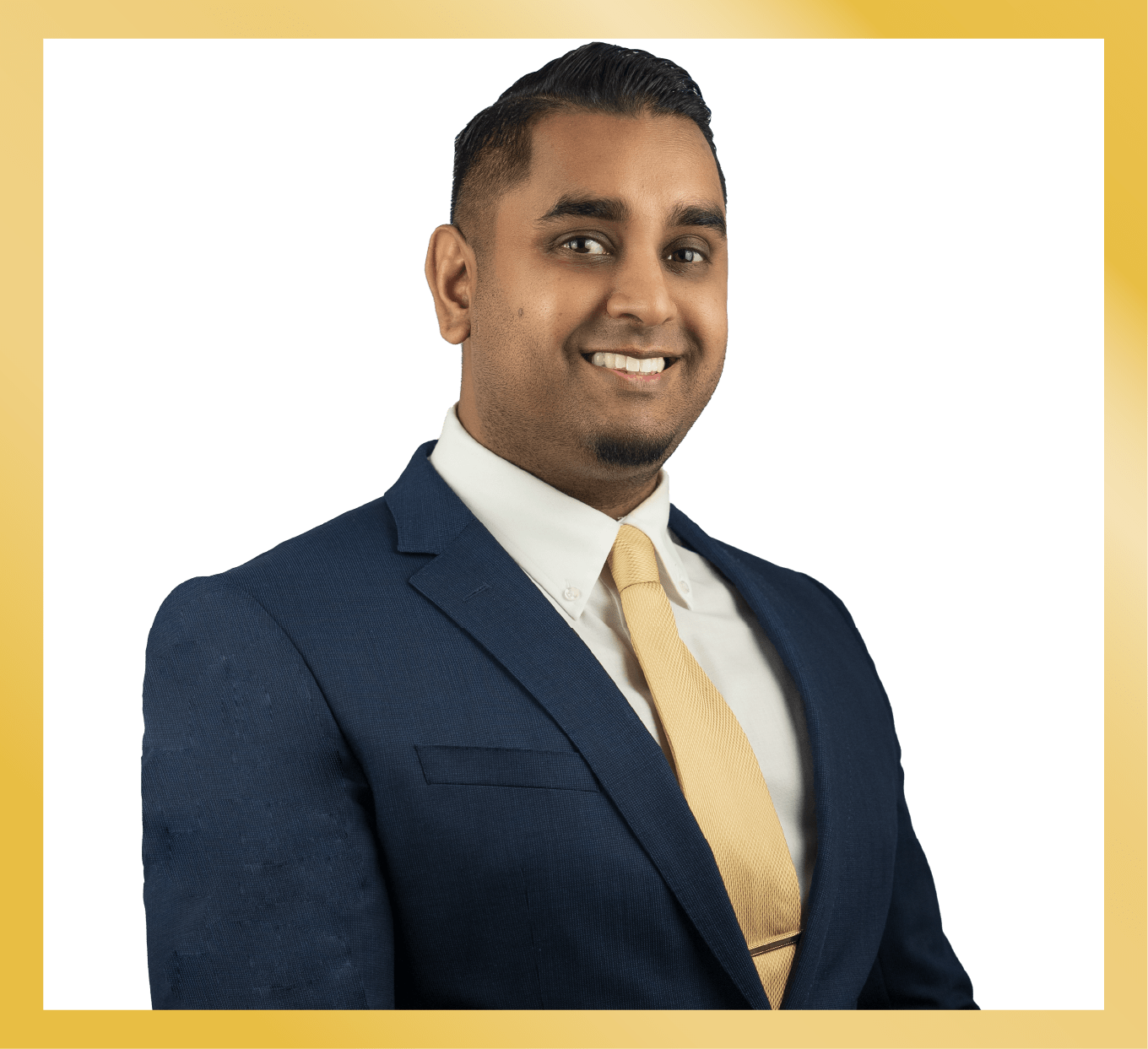 Professional portrait of a man in a navy suit and gold tie, smiling while standing against a white background with a gold rectangular frame.